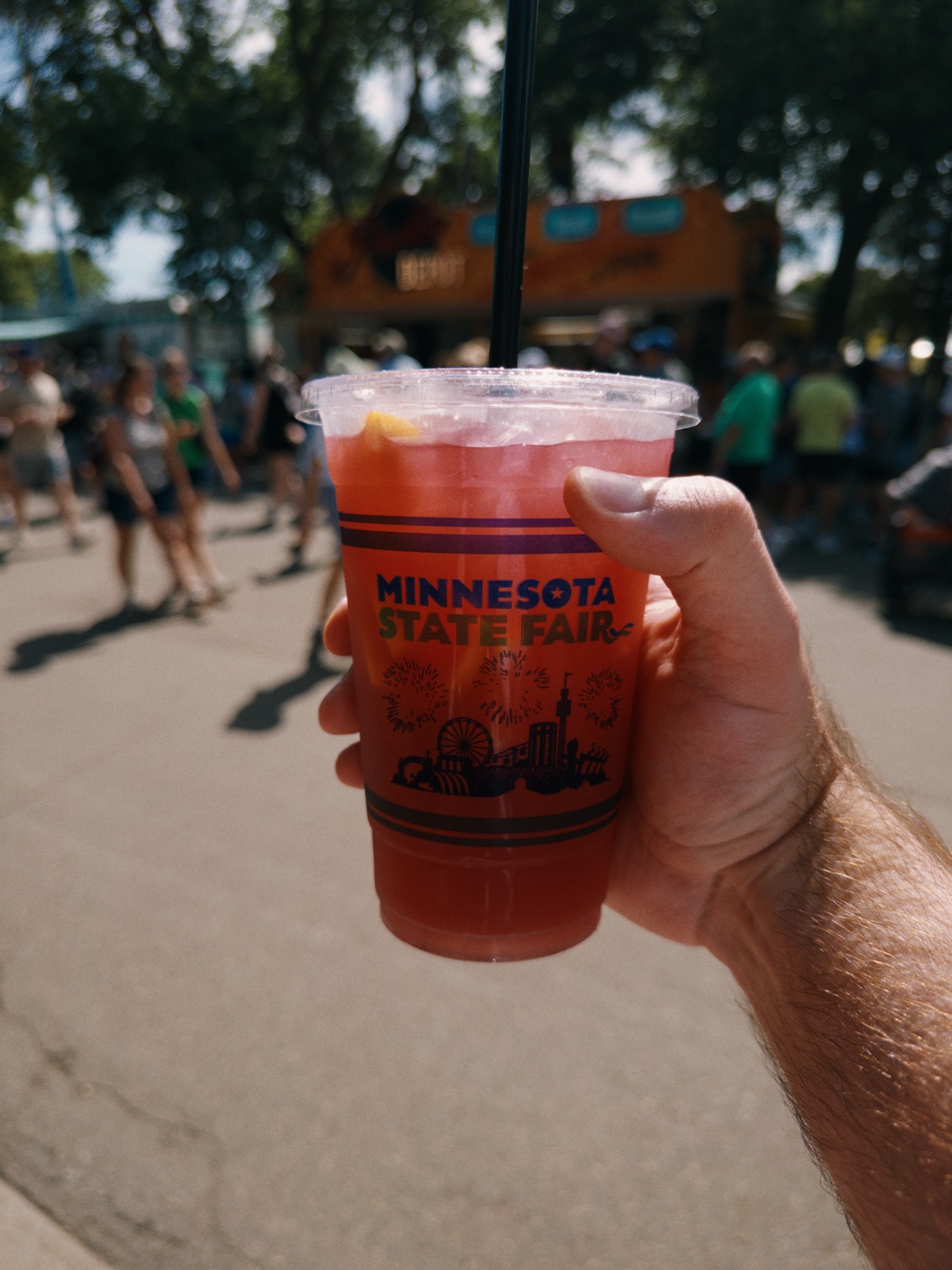 Pink iced drink with an orange wedge in a clear cup with the Minnesota State Fair wordmark