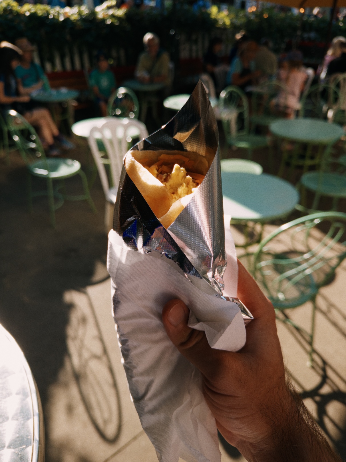 Folded crêpe filled with scrambled egg, cheese, and bacon pieces, wrapped in aluminum foil
