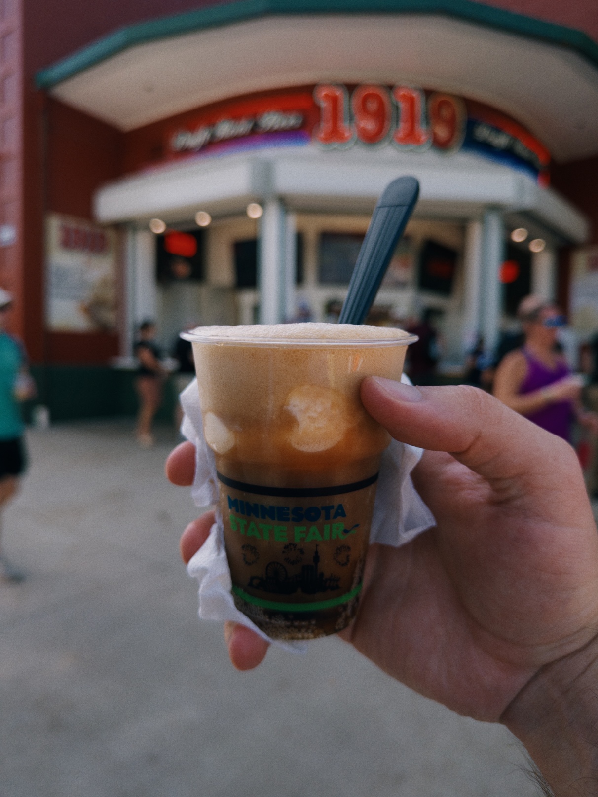 Foamy brown soda with scoops of vanilla ice cream in a clear cup