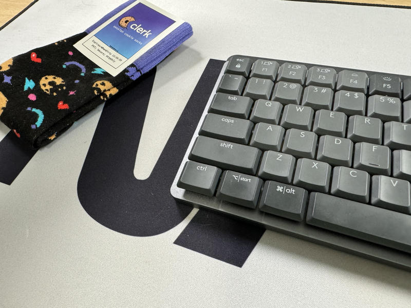Close up photo of the bottom row of keys on the Logitech MX Mechanical Mini keyboard. To the left of the keyboard is a pair of Clerk cookie socks.